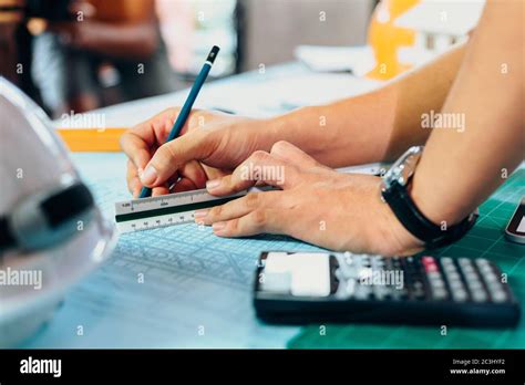 Ingenieure halten einen Stift der auf ein Gebäude zeigt und zeichnen