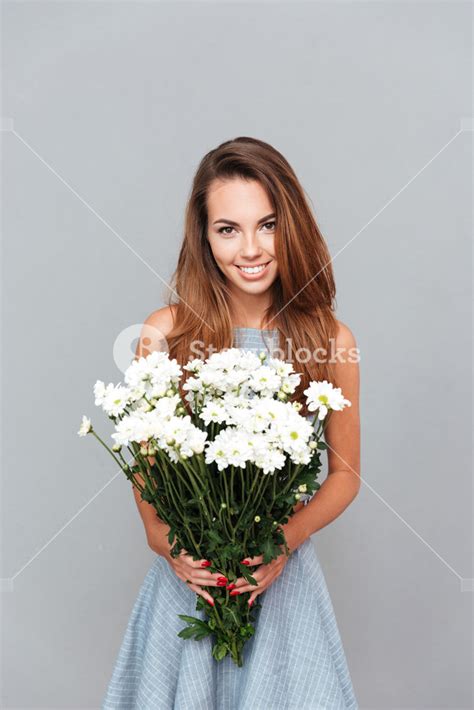 Happy Beautiful Young Woman Holding Bouquet Of Flowers Over Grey