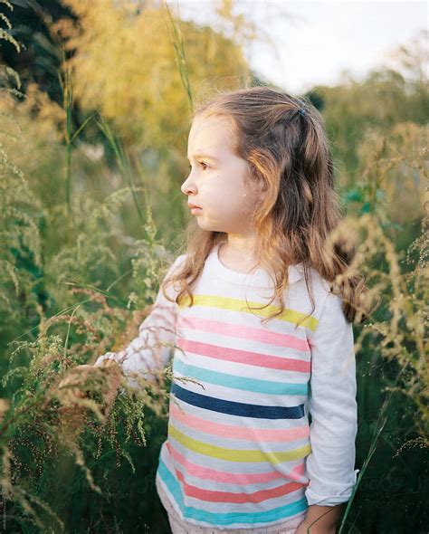 Portrait Of A Beautiful Young Girl Playing In A Field Of Tall Grass