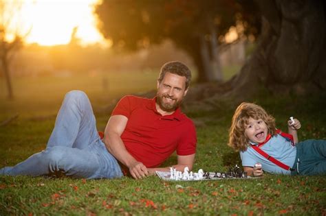 Père et fils jouant aux échecs sur l herbe dans le parc fête des pères