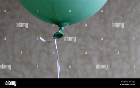 Soft Focus To Bottom Part Of Green Balloon With Rubber Tail Tied Knot With Long String On