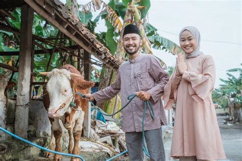 Woman In Hijab Standing Beside The Man That Holding The Cowand X27s