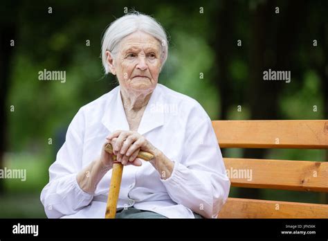 ältere dame sitzt auf einer parkbank Fotos und Bildmaterial in hoher