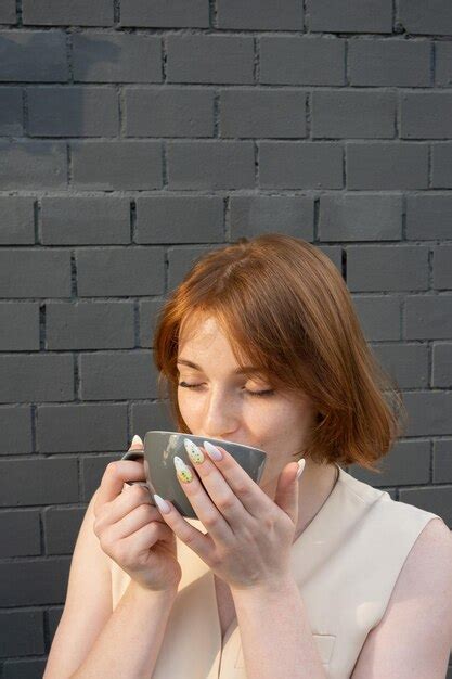 Premium Photo Young Woman With Cup In Hands Enjoying Coffee Tea Or