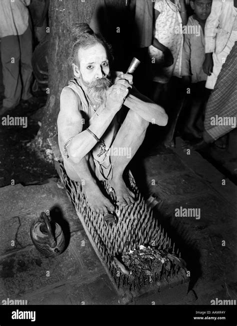 1930 hombre santo hindú fakir sentado en la cama de clavos y clavos de