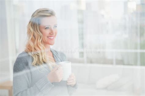 Smiling Blonde Woman Holding Mug Of Coffee Looking Away Stock Photo