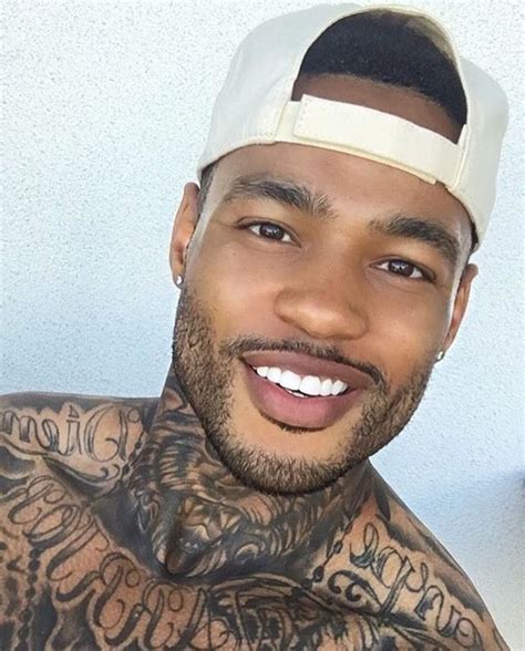 A Close Up Of A Person With Tattoos On His Chest And Head Wearing A Hat