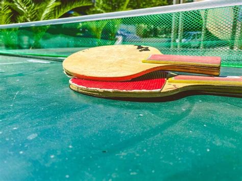 Pequeñas raquetas rojas de tenis de mesa yacen en una mesa hecha de