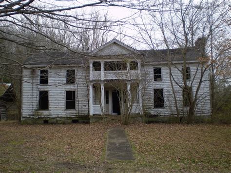 an old white house in the woods with no leaves on the ground and trees ...