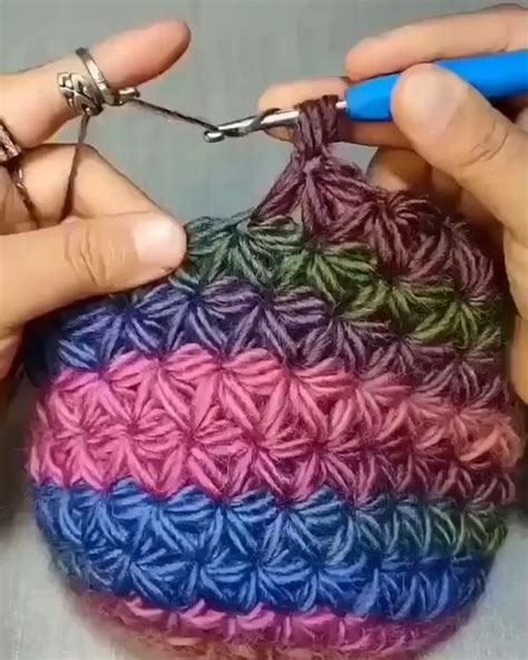 Someone Crocheting A Small Bag With Yarn On The Side And Two Hands