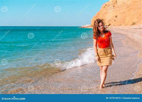 Charming Brunette Woman Walks Along The Beach And Admires The Azure