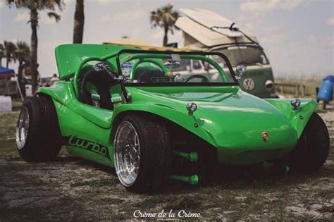 A Green Race Car Parked In Front Of A Bus