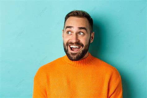 Surprised Man In Orange Sweater Looks At Logo On Turquoise Background