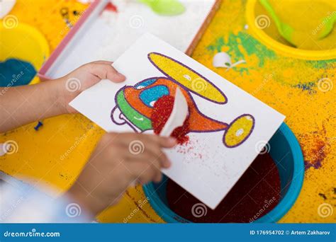 A Child Draws With Colored Sand Picture Cartoon Characters Stock