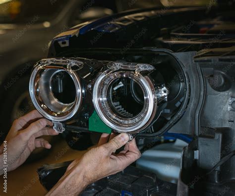 Car headlight in repair close-up. The car mechanic installs the lens in the headlight housing ...