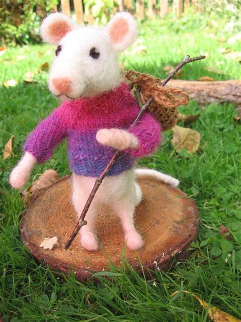 A Stuffed Mouse Holding A Stick On Top Of A Tree Stump