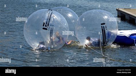 Kids Playing Inside Tethered Inflatable Bubbles On Dock Water At Aqua