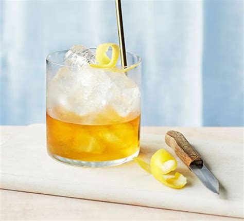 A Glass Filled With Ice And Lemons Next To A Knife