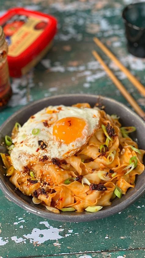 An Egg Is On Top Of Noodles In A Bowl With Chopsticks Next To It