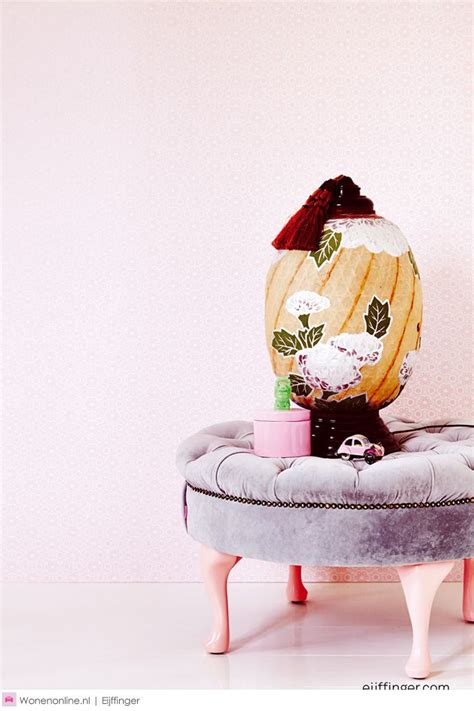 An Egg Sitting On Top Of A Stool In Front Of A Wall With Pink Walls