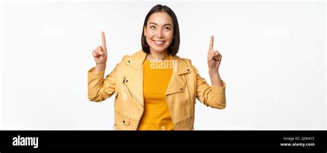 Image Of Smiling Asian Brunette Woman Pointing Fingers Up Showing Advertisement With Happy Face