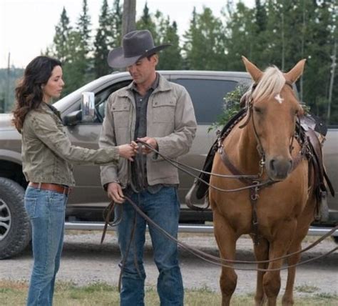 A Man And Woman Standing Next To A Brown Horse In Front Of A Gray Truck