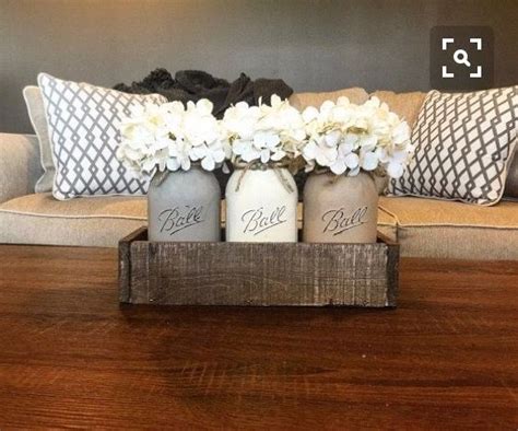 Three Mason Jars With Flowers In Them Sitting On A Coffee Table Next To