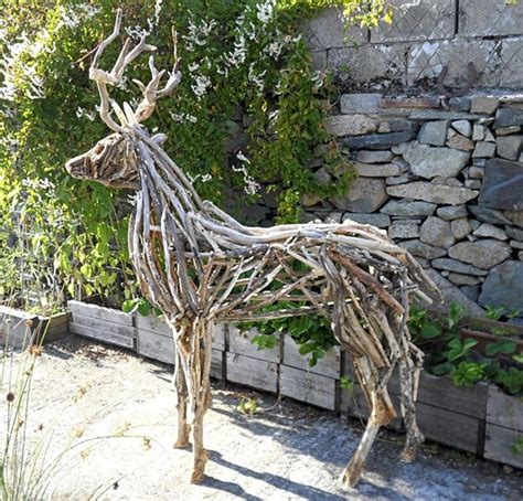 A Wooden Sculpture Of A Deer Made Out Of Branches In Front Of A Stone Wall