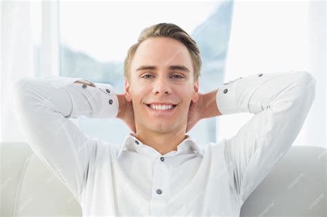 Premium Photo Smiling Relaxed Young Man Sitting On Sofa In House