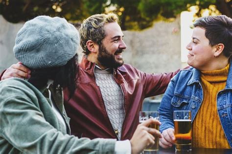 Grupo de jovens amigos reunidos em um café ao ar livre bebendo cerveja