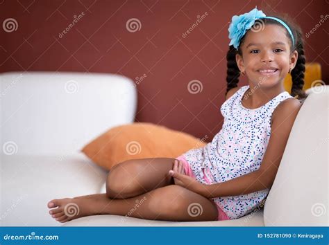 Cute African American Girl Sitting On A Couch And Smiling Stock Photo