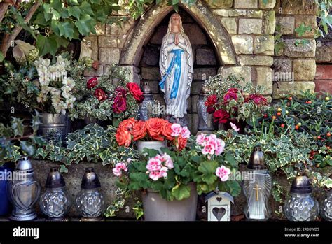 Statue Of The Blessed Virgin Mary Set Inside A Small Enclave And Surrounded By Flowers England