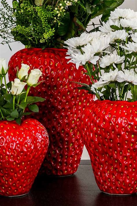 Three Strawberry Shaped Vases With Flowers In Them