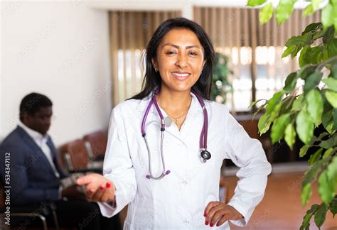 Smiling Hispanic Female Doctor Wearing White Coat With Phonendoscope On