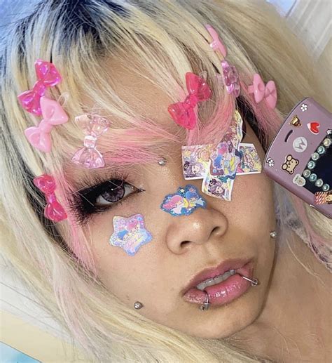 A Woman With Pink And Blue Hair Has Stickers On Her Face While Holding