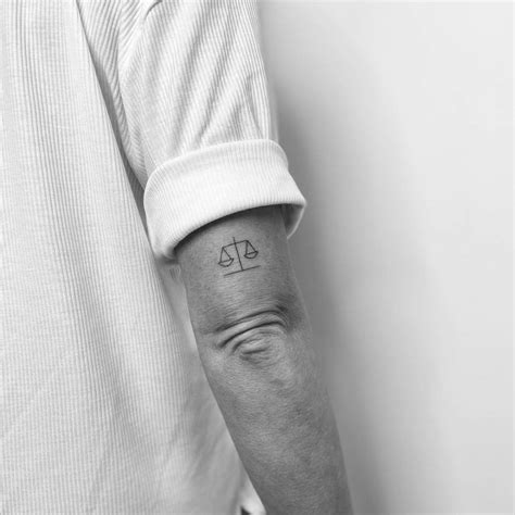 Minimalist scale tattoo on the tricep.