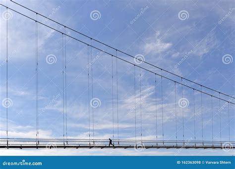 A Bridge Over a River with a Man Walking Along it Against a Blue Sky. Stock Photo - Image of ...