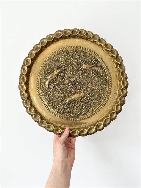 A Person Holding Up A Gold Plate With Designs On The Bottom And Sides