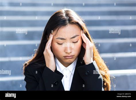 Young Beautiful Asian Woman Upset And Sad Sitting On The Stairs Of The