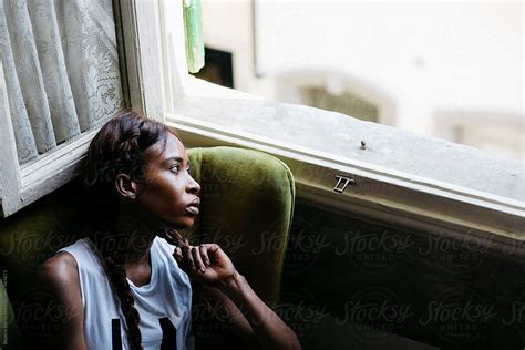 "Young Black Woman In An Armchair Looking Out Of The Window" by Stocksy ...