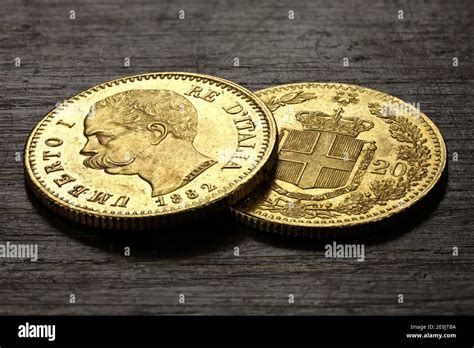 Italian 20 Lira gold coins on rustic wooden background Stock Photo - Alamy