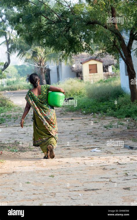 Indian Woman Carrying A Plastic Pot With Water From A Hand Pump In A