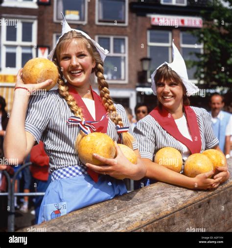 Two Dutch Girls In Traditional Dress Selling Cheeses At Alkmaar Market