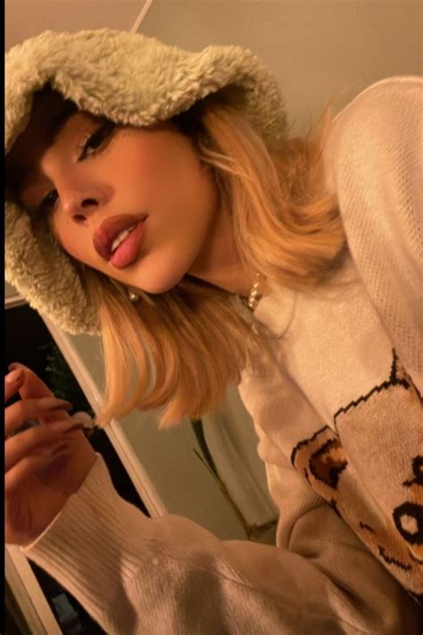 A Woman Wearing A Hat And Sweater Is Taking A Selfie