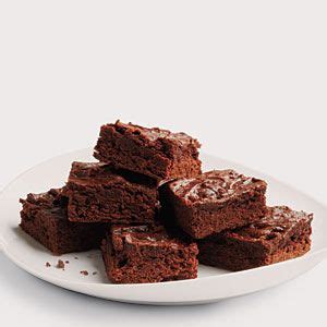 A White Plate Topped With Brownies Covered In Frosting