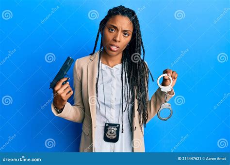 African American Police Woman Holding Gun And Handcuffs In Shock Face