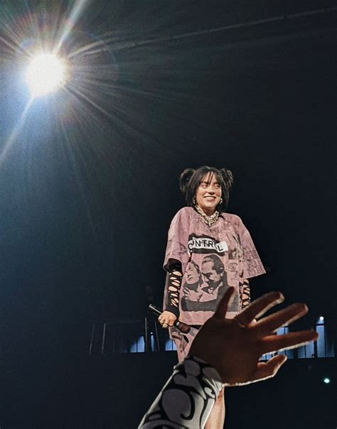 a woman standing on top of a stage holding her hand up