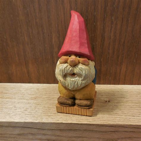 A Gnome Figurine Sitting On Top Of A Wooden Shelf