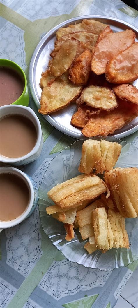 Two Plates Filled With Fried Food Next To Cups Of Tea And Sauces On A Table