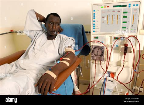 A Man Lays Patiently While Attached To A Dialysis Machine The Image